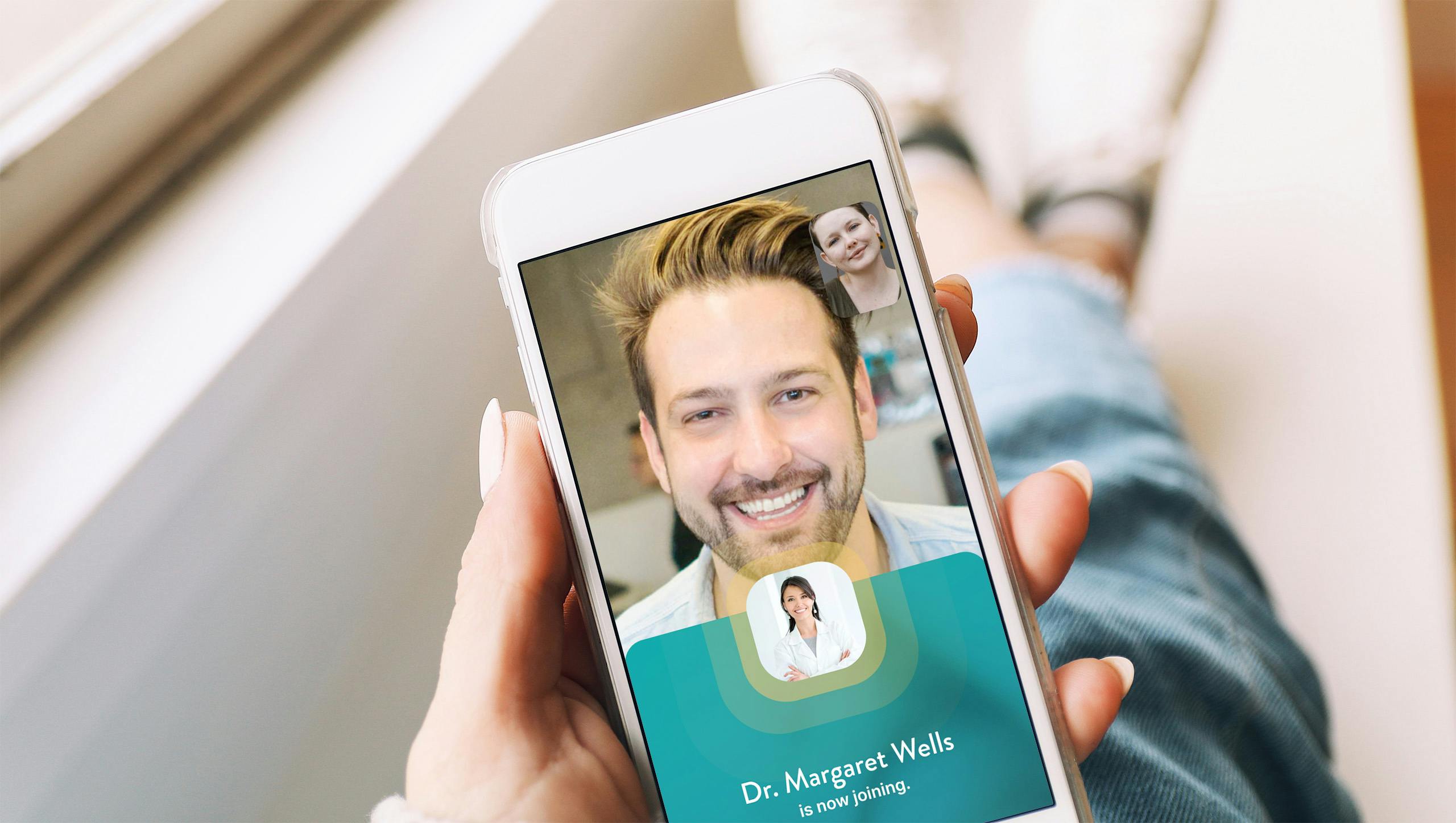 A hand holding a phone with a screen showing a person smiling and the words Dr. Margaret Wells is now joining.