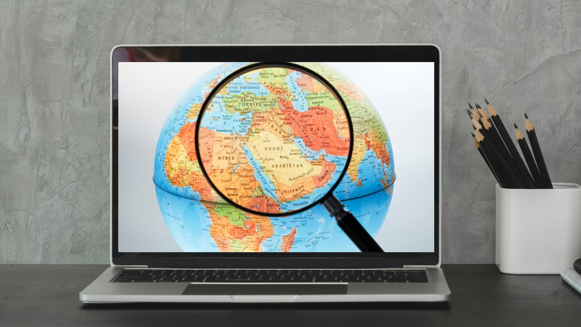 laptop showing an image of a globe and a magnifying glass highlighting the West Asia region of the world