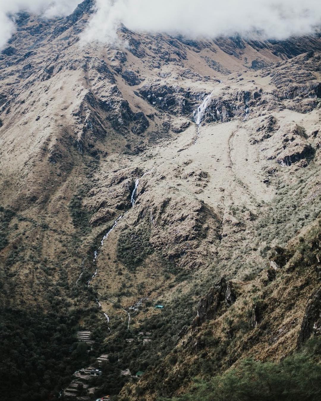 The side of a mountain with a waterfall running down it.