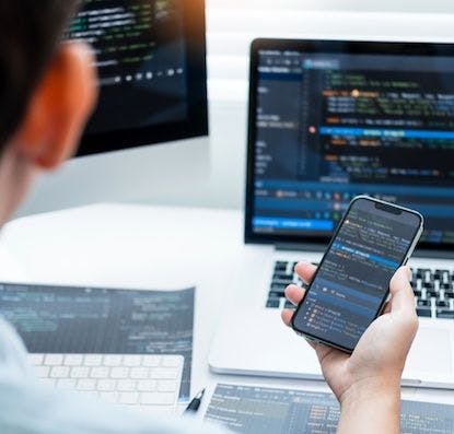 A developer checks that code runs properly on both a laptop and a mobile device