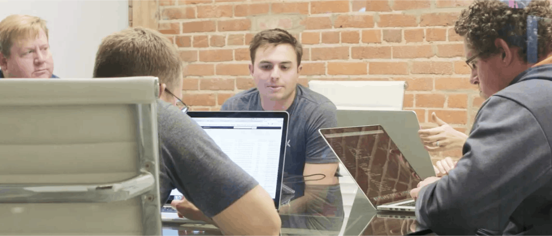 A group of people at a conference table, each with a laptop open